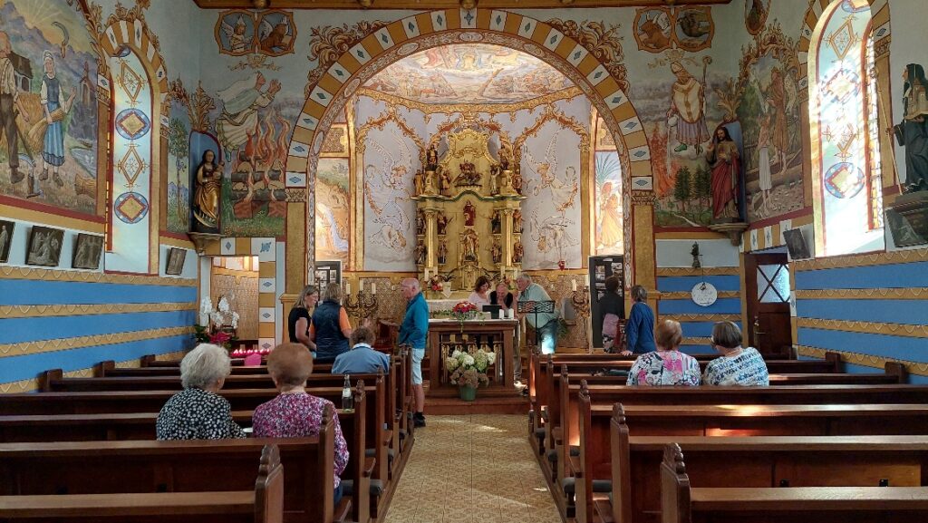 Innenansicht der reich bemalten Kapelle in Wawern mit kunstvollen Wandmalereien, barockem Altar und interessierten Besuchern am Tag des offenen Denkmals.