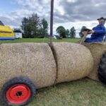Strohtraktor mit Strohfigur auf Dorffest in Wawern (Eifel) – kreative Heuballen-Skulptur mit Traktor-Optik, im Hintergrund Hüpfburg und Festwiese.