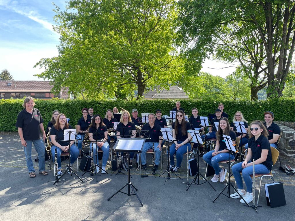 Musikverein Wawern beim Auftritt im Freien – junge Musikerinnen und Musiker mit Instrumenten unter Bäumen bei sonnigem Wetter